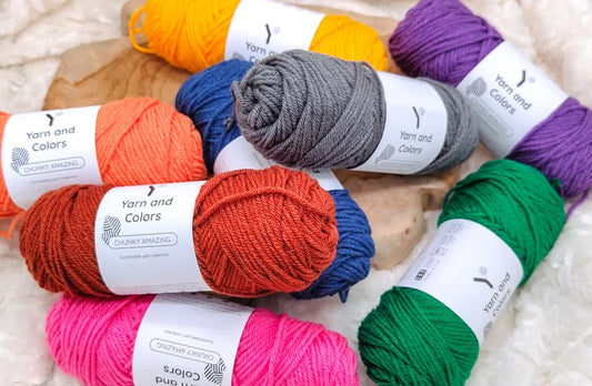 Meerdere bollen Yarn and Colors Chunky Amazing in verschillende kleuren die op en door elkaar liggen op een houten ondergrond