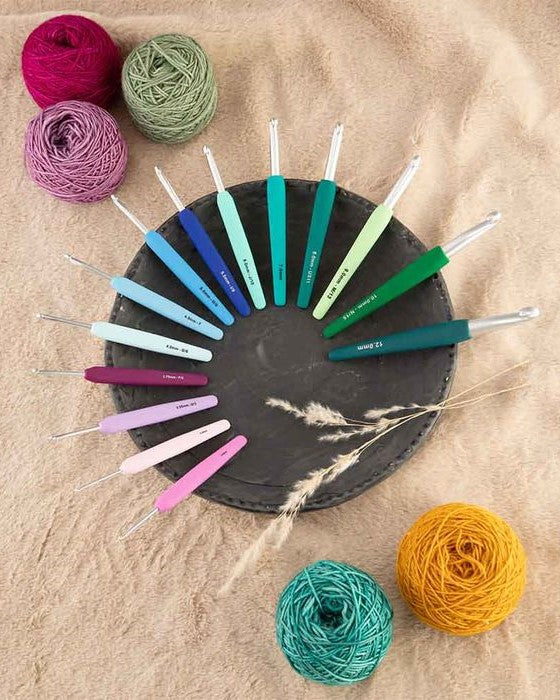 Alle KnitPro Waves 2.0 haaknaalden bij elkaar op een zwarte en zandkleurige ondergrond