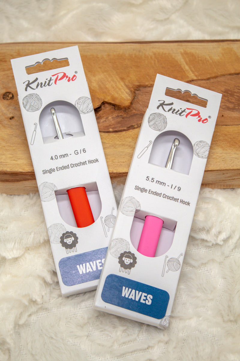 Twee KnitPro Waves haaknaalden in verpakking op een houten ondergrond