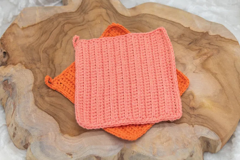Oranje en licht oranje gehaakte pannenlappen gemaakt met  Haakpatroon pannenlap Ridge ontworpen door Cora's Knit Knacks