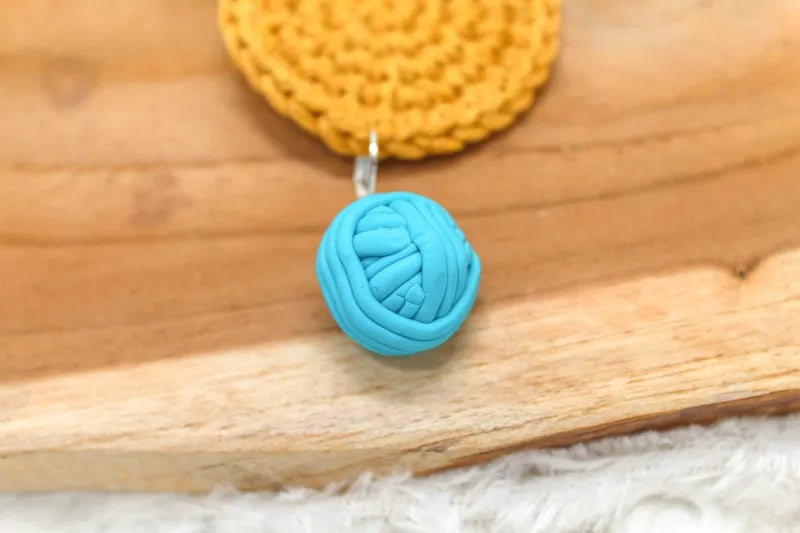 Handgemaakte steekmarkeerder van een blauw bolletje wol, handgemaakt door Beaudeleine