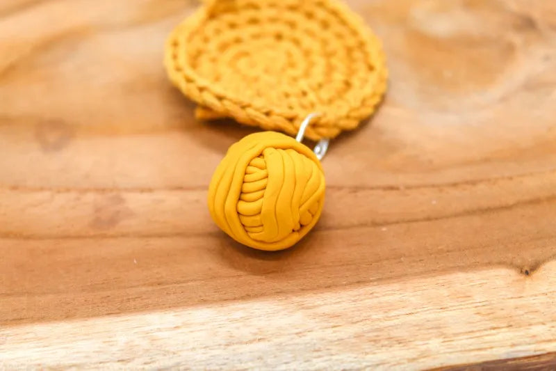 Handgemaakte steekmarkeerder van een geel bolletje wol, handgemaakt door Beaudeleine