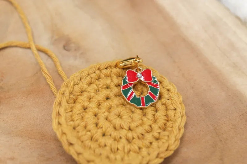 Handgemaakte steekmarkeerder kerstkrans op een geel rondje, handgemaakt door Studio Kellebel