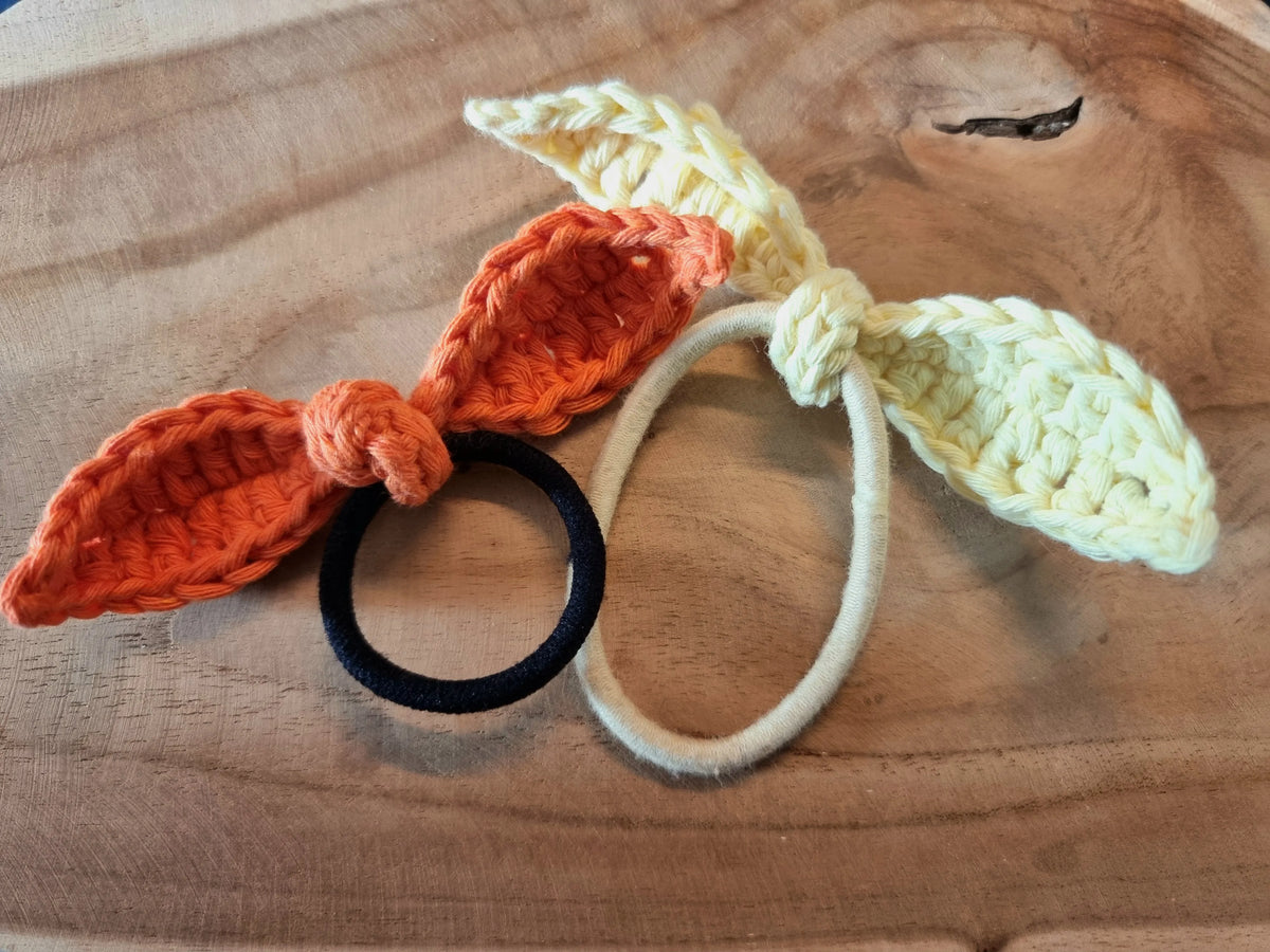 Oranje en licht geel gehaakte strikjes naar Haakpatroon strikje Sisi ontworpen door Cora's Knit Knacks