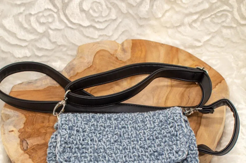 Vegan leren tassenriem met verstelbare band en metalen haken aan blauwe tas.