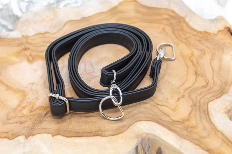 Vegan leren tassenriem, zwarte band met metalen ringen en sluiting.