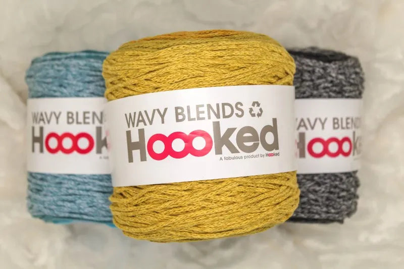 Drie kleuren Hoooked Wavy Blends die op elkaar liggen: blauwtinten, zwarttinten en geeltinten