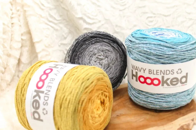 Duurzaam garen: Hoooked Wavy Blends in verschillende kleuren op een houten ondergrond