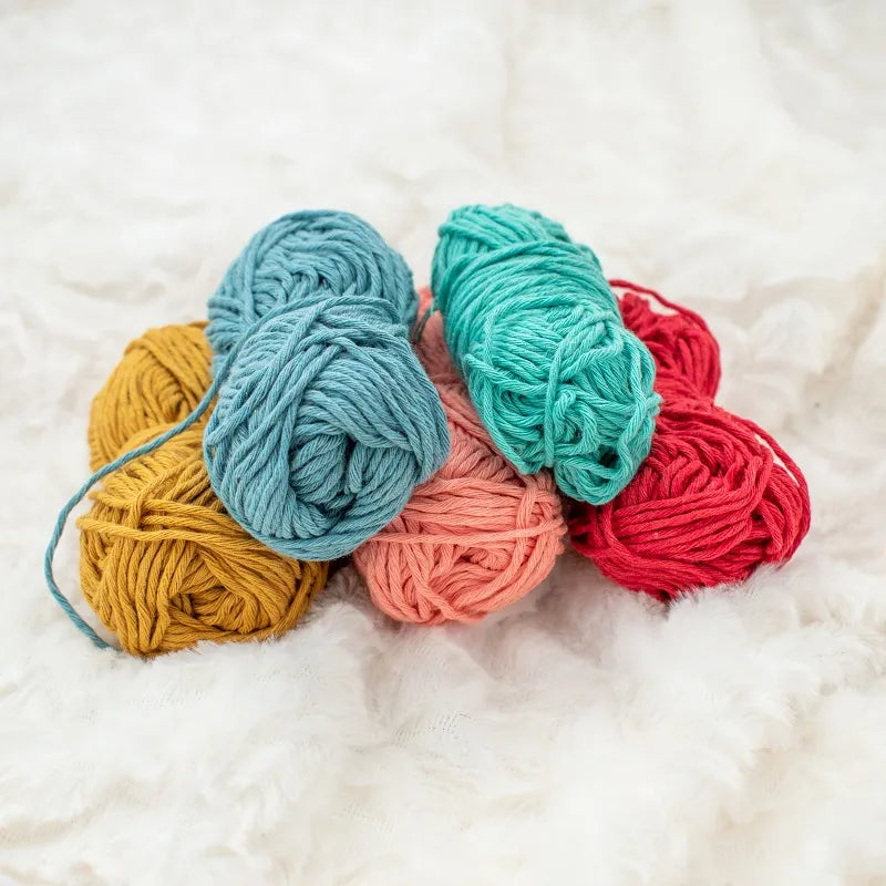 Vijf kleuren Hoooked Soft Cotton DK gerecycled katoen garen bij elkaar: okergeel, licht oranje, rood, turkoois en jeans blauw