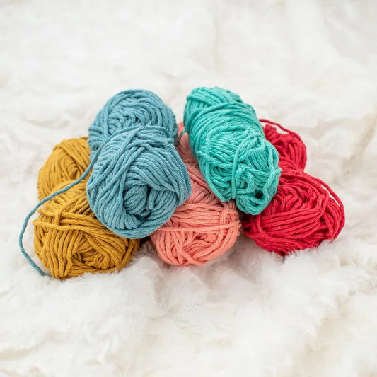Vijf kleuren Hoooked Soft Cotton DK gerecycled katoen garen bij elkaar: okergeel, licht oranje, rood, turkoois en jeans blauw